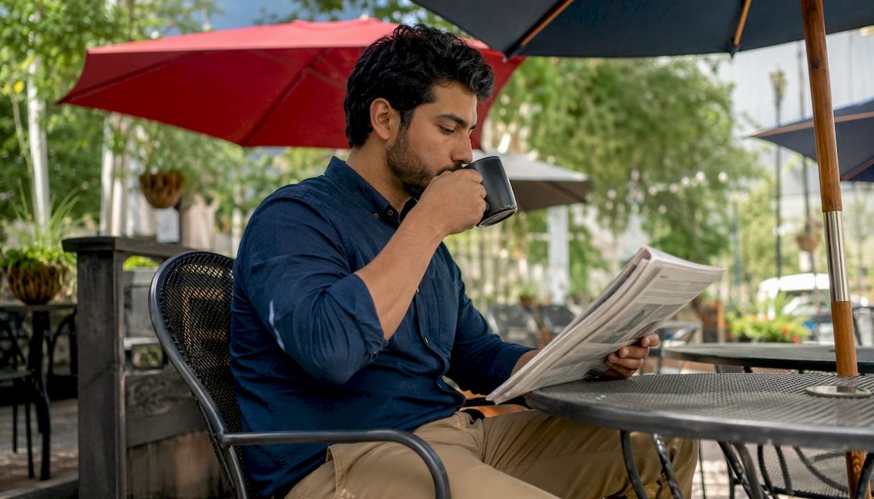 Man reading local news newsletter at café